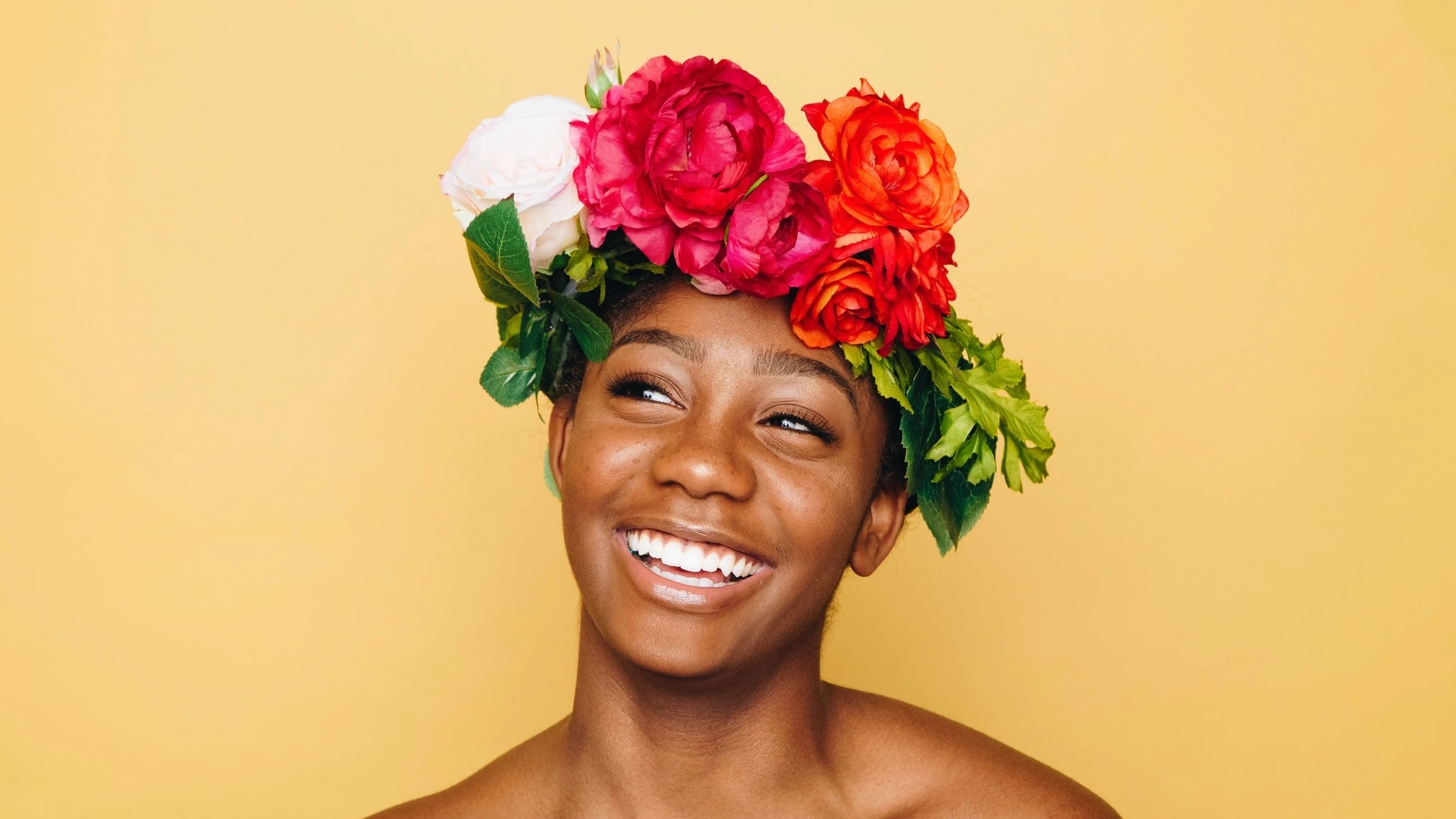 Femme de couleur souriante avec des fleurs sur la tête